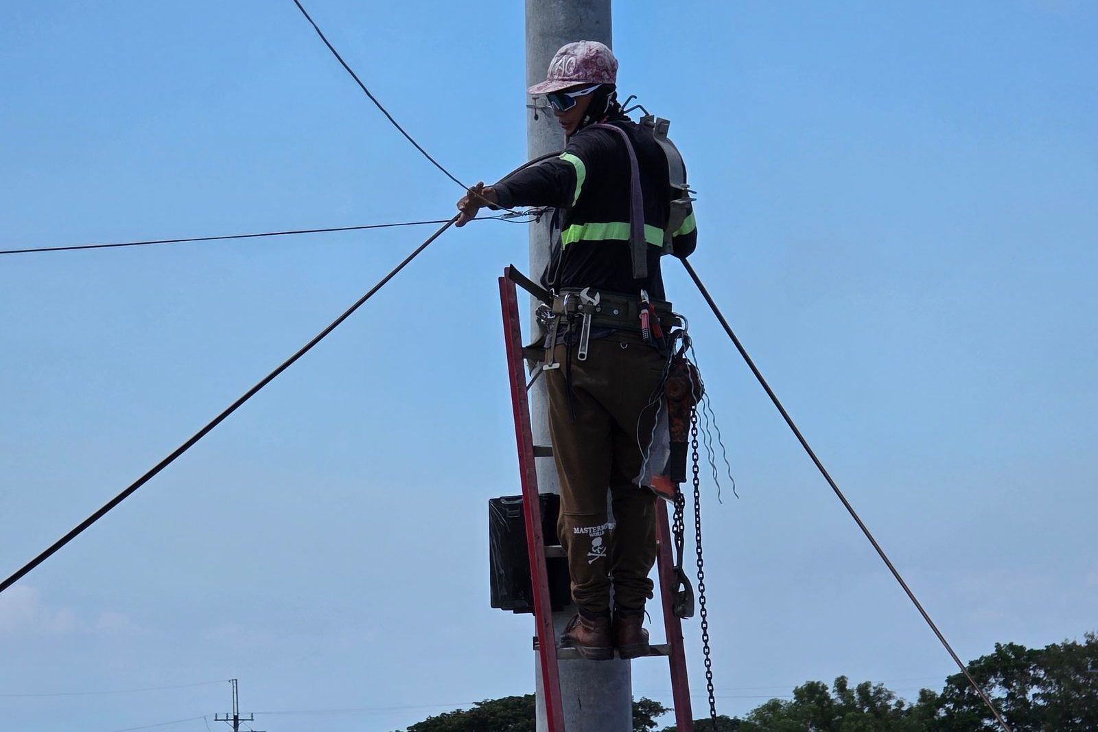 Lineman pulling fiber cable on a utility pole